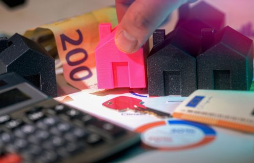 Miniature houses, Euro bills, and calculator representing real estate investment.