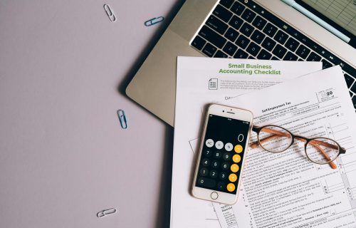 pexels photo 8962451 8962451 Flat lay of small business accounting tools including tax form, phone, and glasses on a desk.